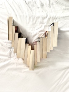 Books on a white bed with the pages facing outwards, arranged in the shape of a heart. 
